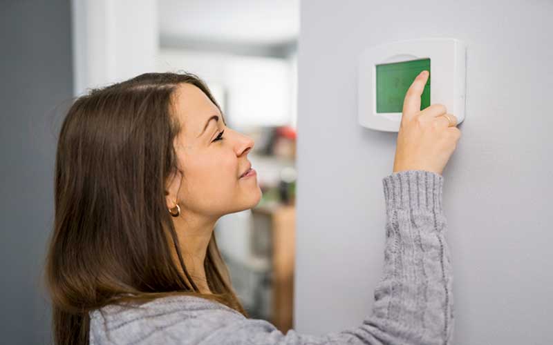 woman adjusting thermostat