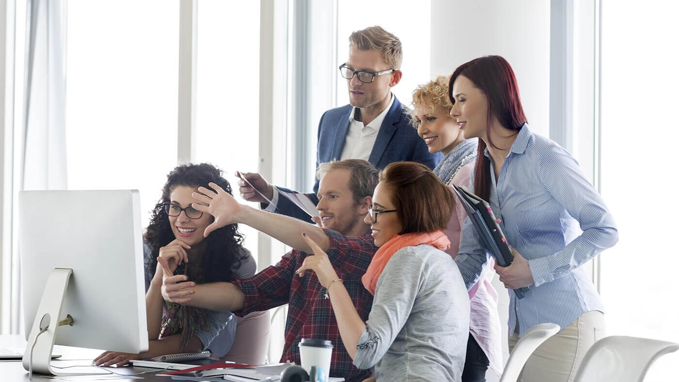 group of people and designer sitting around a computer